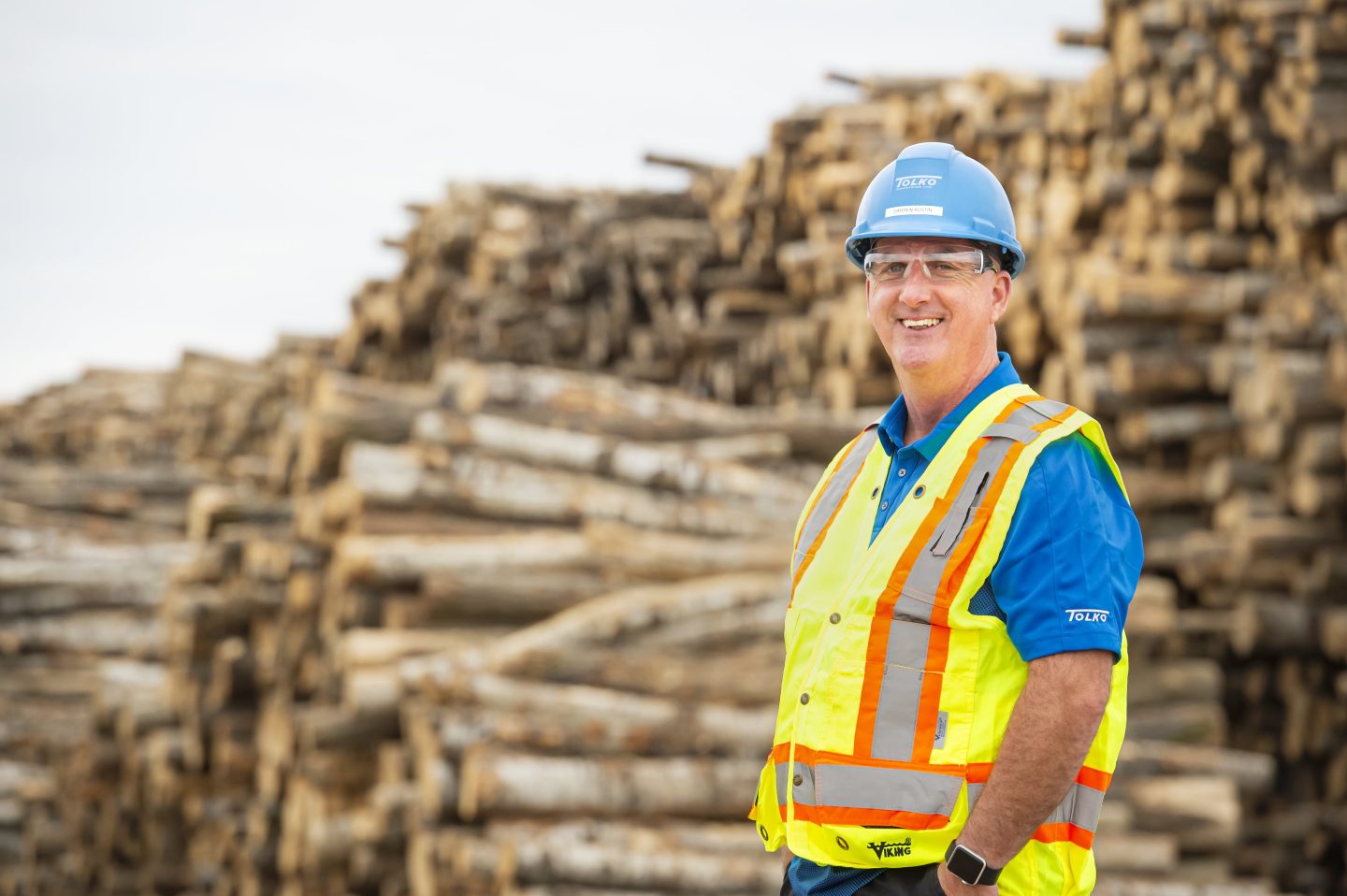 A forestry worker standing in front of stacked lumber, representing Saskatchewan’s forestry industry.