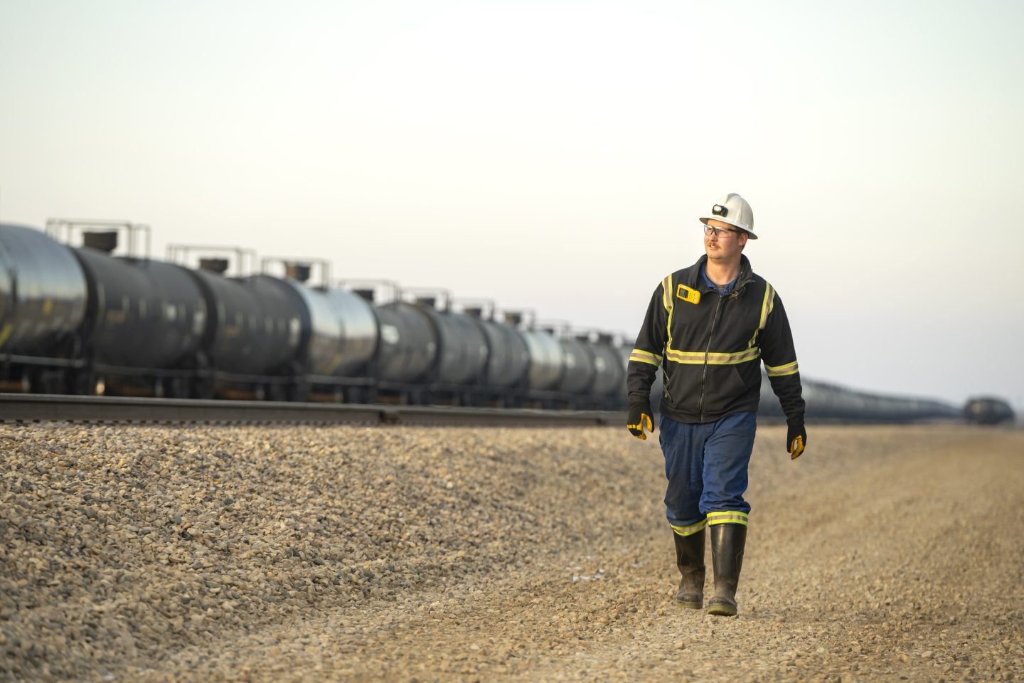 An energy worker standing alongside a rail line, representing Saskatchewan’s diverse economic sectors, including energy, transportation, and infrastructure.