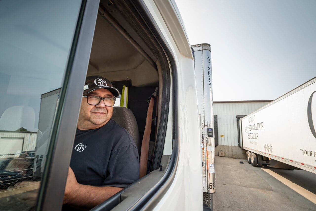 a man driving a semi truck transporting goods.