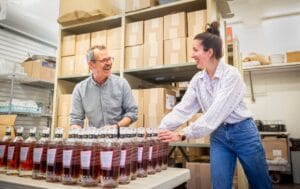 People packaging goods at a work table, placing products into containers as part of a small scale production or distribution process.