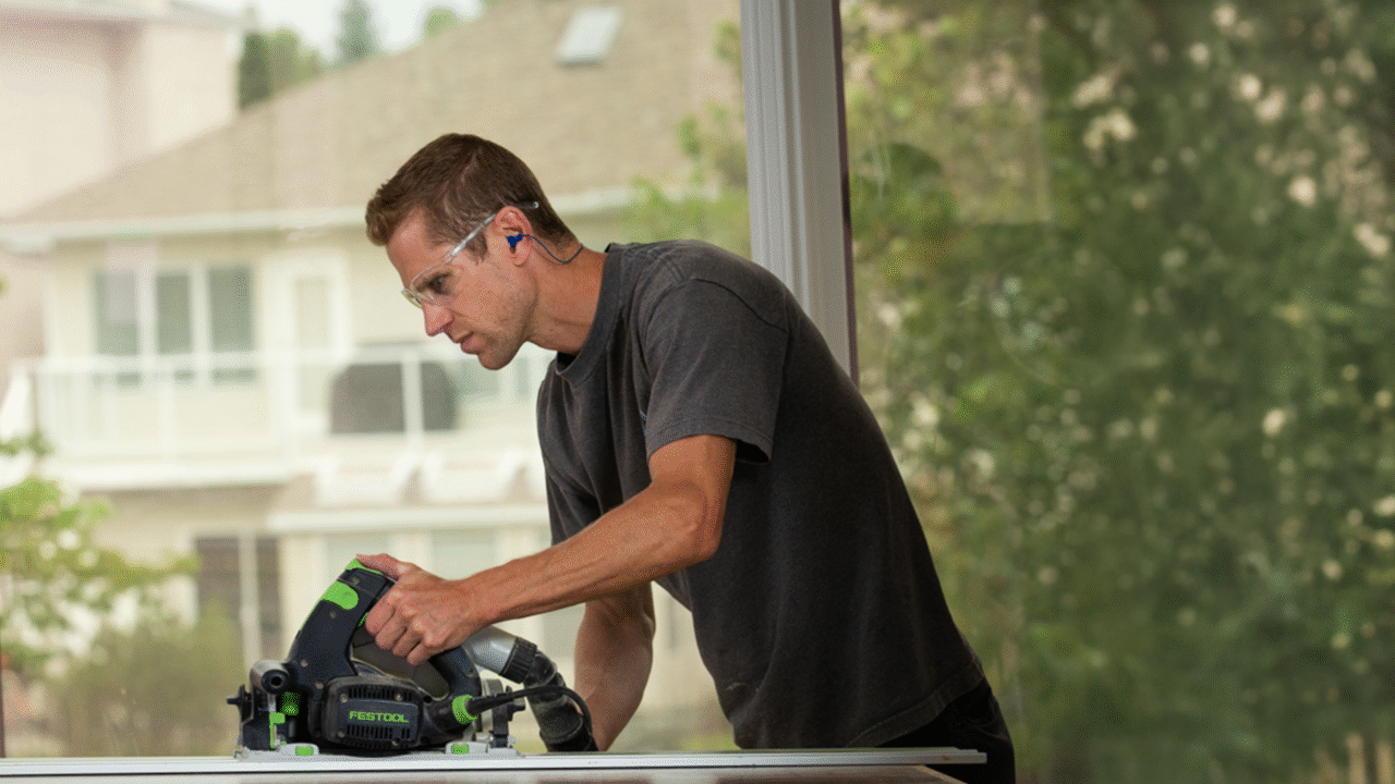 A worker cuts lumber inside a partially built home, illustrating that Saskatchewan ranks first among provinces for housing starts.