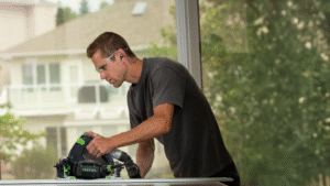 A worker cuts lumber inside a partially built home, illustrating that Saskatchewan ranks first among provinces for housing starts.